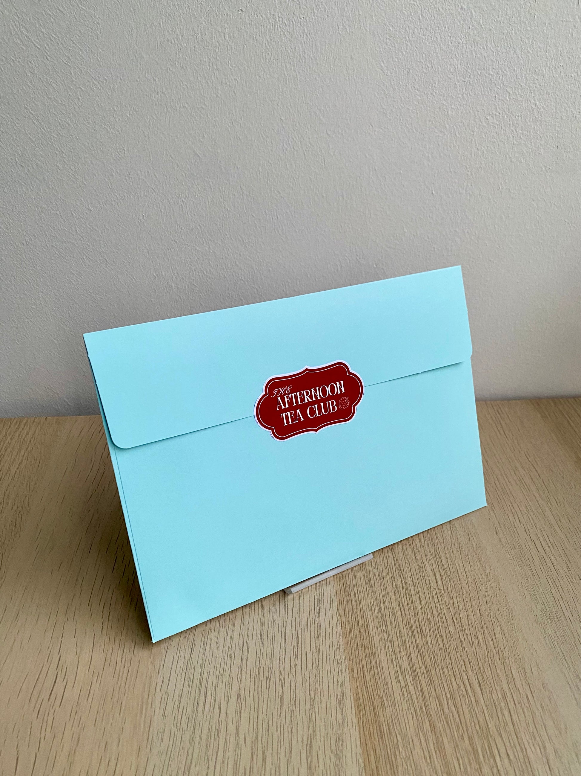 Light blue envelope with a red label on a wooden surface