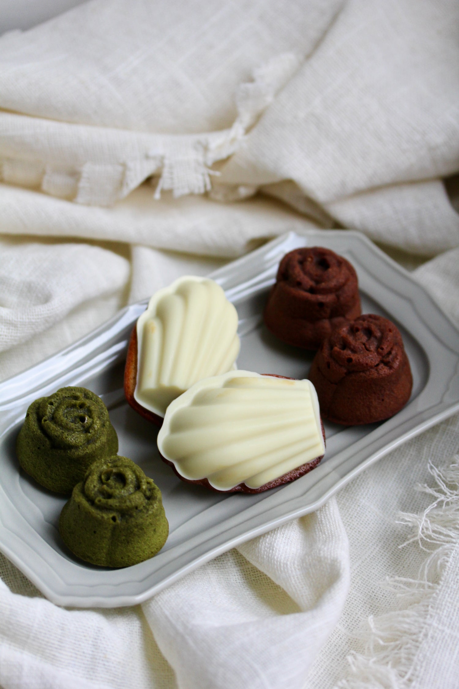 Assorted colorful pastries on a white tray with a white fabric background